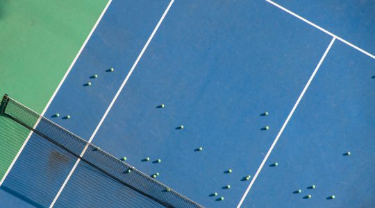 Aerial shot of tennis court with active youth